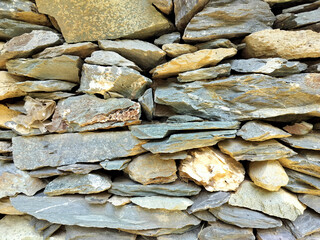 Rough old stone wall with textured gray brown rock surface  details in natural pattern
