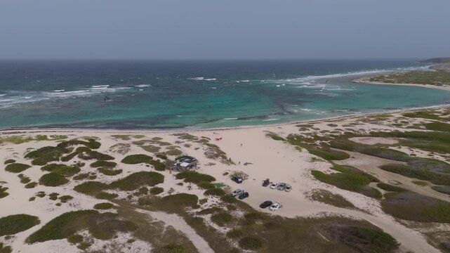 Kitesurfing and parked vehicles on Boca Grande beach in Aruba