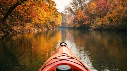 A person kayaking down a river with autumn trees nearby