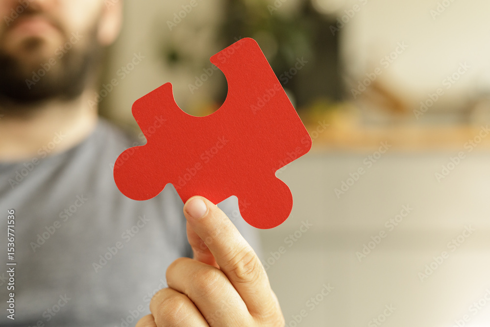 Poster A man holds a single red puzzle piece, symbolizing a missing piece, solution, or problem.  Ideal for business, strategy, and problem-solving concepts.