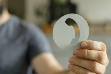 Close-up of a person holding a paper cutout of a phone icon, representing communication or contact.