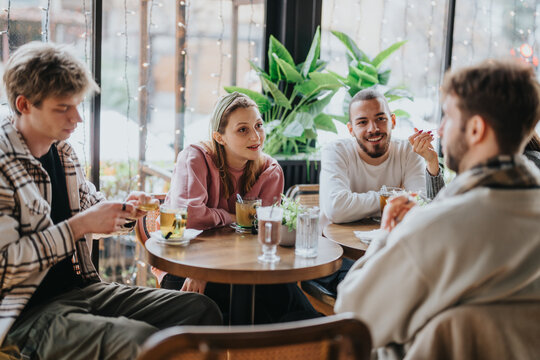 A group of friends sitting together at a modern cafe, sharing drinks and conversation in a cheerful ambiance. The setting is warm and inviting, enhanced by natural light and decorative plants.