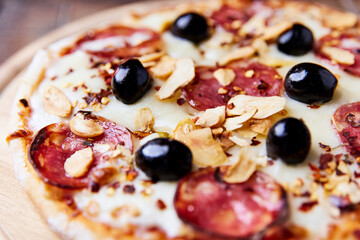 Pizza with salami and mozzarella cheese. Wooden background. Soft focus. Close up.