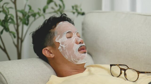 Asian man wearing sheet mask while video calling friends.4k