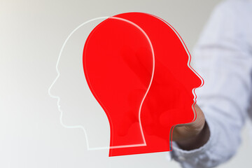 Stock photo of two head silhouettes, one red, one white, representing diverse viewpoints or collaboration.