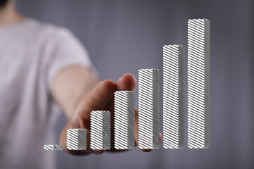 Stock photo of a hand presenting a 3D bar graph showing business growth and progress.