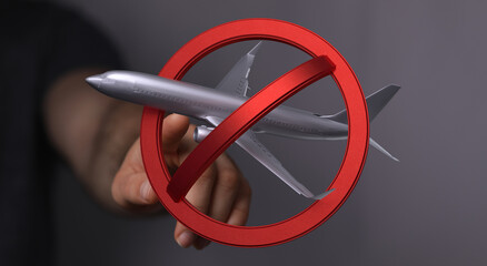 Image of a hand holding a no symbol over a model airplane, representing travel bans or restrictions.