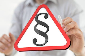 Stock photo of a hand holding a digital warning sign with a paragraph symbol, representing legal...