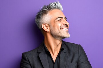 Fototapeta premium Purple solid background. A sophisticated gentleman in a well-lit studio. Modish men's spiky hair haircut - midlife arabian man with short hair. Idea of style for aging men.