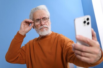 Senior man with vision problem using smartphone at home