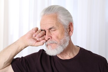 Senior man suffering from eyestrain at home