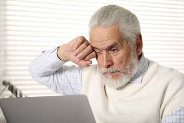 Senior man with vision problem using laptop at home