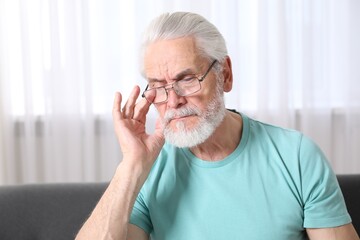 Senior man in glasses suffering from eyestrain at home