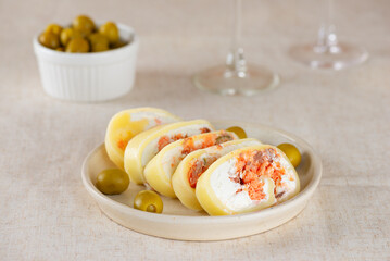 Farm cheese roll with salmon, olives and cream cheese in a plate.