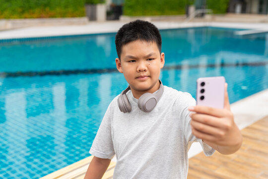 Teenage Boy at Poolside During Summer Using Phone
