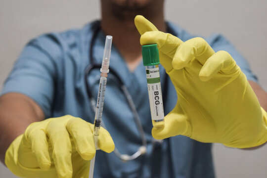 Text BCG vaccine of is written on a bottle with background of a doctor with a syringe in a medical glove mask. Medical concept