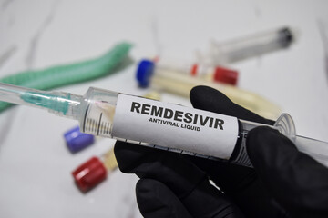 Remdesivir antiviral liquid drug syringe in black gloved hands. Medical concept