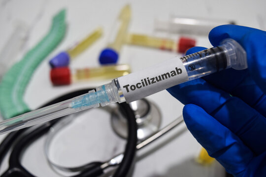 Tocilizumab drug syringe in blue gloved hands. Medical concept