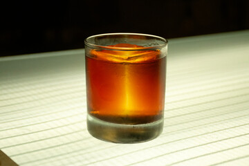 close up of campari negroni cocktail with translucent ice on illuminated counter in pub