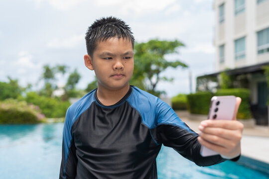 Asian teenage boy using phone after swimming in pool