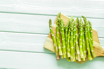 Cooking asparagus. Fresh steams on cutting board on green wooden background top-down copy space