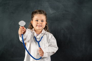 Little cute girl with stethoscope and medical uniform with black background.