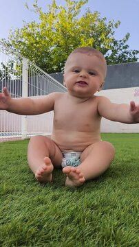 Ni&ntilde;o gracioso gateando arrastrando el culo por el c&eacute;sped artificial