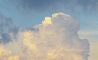 Golden-yellow clouds glow in the evening sky, illuminated by the warm rays of the setting sun,...