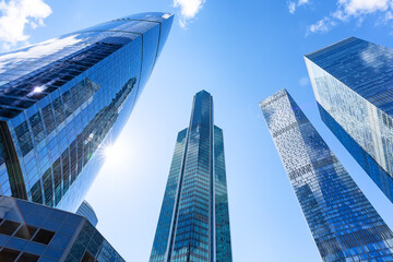Low angle view of modern skyscrapers against blue sky. Reflective skyscrapers, business office buildings.