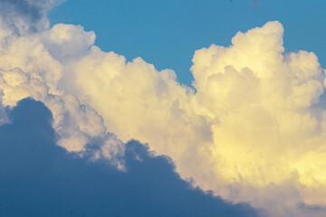 Golden-yellow clouds glow in the evening sky, illuminated by the warm rays of the setting sun,...