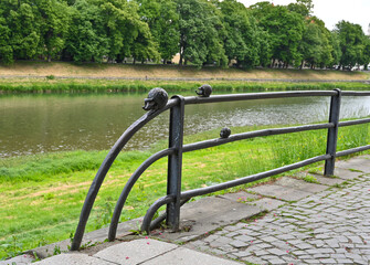 Unique sculptures on a riverfront railing in a city park during daytime