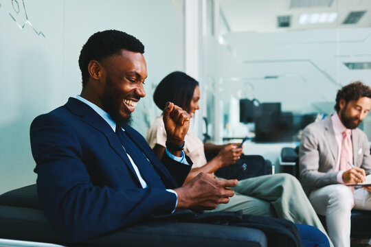 Happy businessman celebrating success on smartphone in office lobby