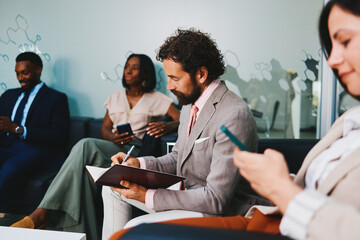 Businesspeople using smartphones and taking notes in office lobby