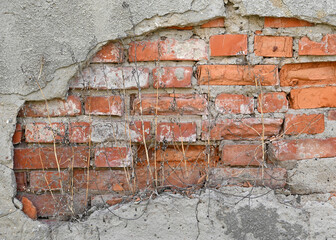 Wall with visible brick damage and rough texture in an outdoor setting during daylight
