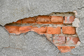 Wall with visible brick damage and rough texture in an outdoor setting during daylight