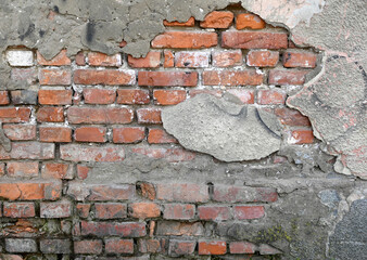 Wall with visible brick damage and rough texture in an outdoor setting during daylight