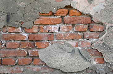 Wall with visible brick damage and rough texture in an outdoor setting during daylight