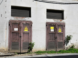 Electric power access doors on a building wall with warning signs in urban area