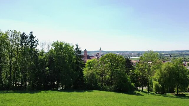 Luftaufnahme von Donauw&ouml;rth mit roten D&auml;chern, historischen Geb&auml;uden und einem markanten Turm, eingebettet in eine gr&uuml;ne Landschaft. Die Stadt bietet eine charmante Kulisse. 