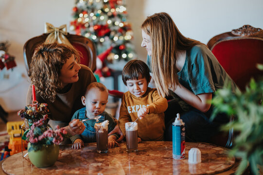 A cheerful family gathering enjoying hot chocolate on a cozy holiday setting with Christmas decorations, celebrating joyful and warm festive moments together.