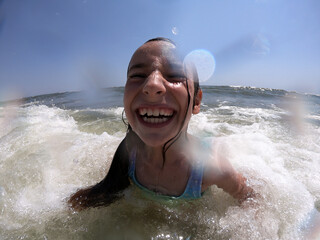 Powerful ocean waves splashing on child girl in summer vacation