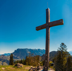 Alpine spring view with a summit cross and Mount Zahmer Kaiser in the background at Kaiserlift Kufstein, Tyrol, Austria