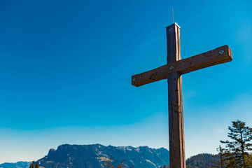 Alpine spring view with a summit cross and Mount Zahmer Kaiser in the background at Kaiserlift Kufstein, Tyrol, Austria