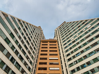 Upward view of contemporary high-rise apartment buildings with geometric lines, glass windows, and...