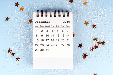 December 2025 calendar on a blue background with golden star confetti and fake snow, representing...