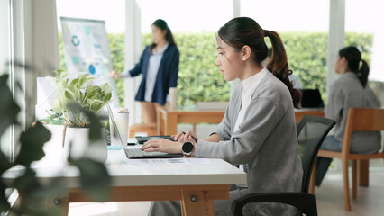 The way forward save the planet earth Gen Z female asia people go green net zero waste control ESG audit office desk. Young adult woman asian SDG carbon credit tax auditor busy happy work using laptop