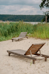 Obraz premium Wooden lounger on a sandy beach by the lake