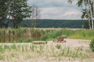 Wooden lounger on a sandy beach by the lake