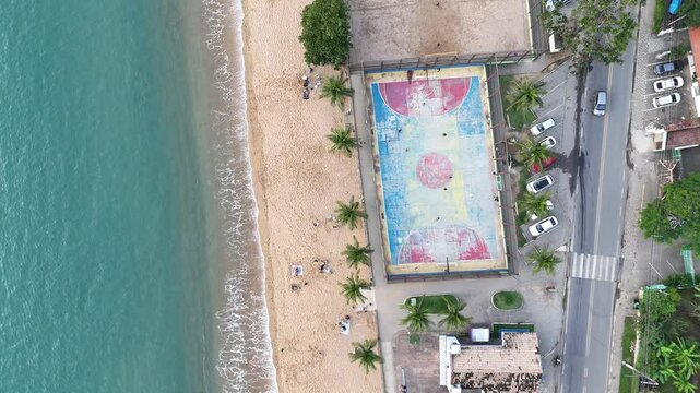 Drone registra partida de futsal em quadra &agrave; beira-mar em Ilhabela, com jogadores em a&ccedil;&atilde;o e paisagem litor&acirc;nea ao fundo em dia ensolarado