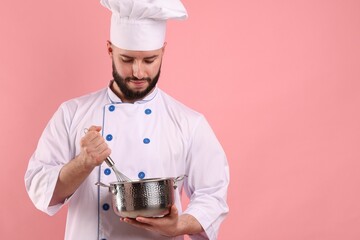 Happy confectioner in uniform holding whisk and cooking pot on pink background